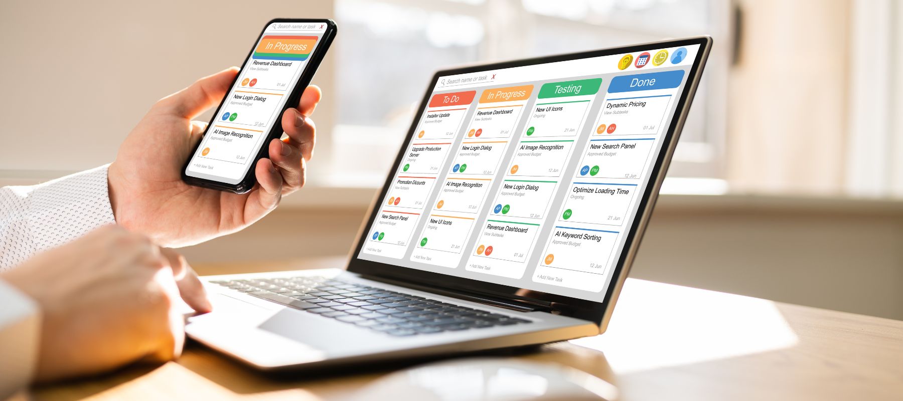 A person holds a smartphone and works on a laptop displaying a digital kanban board with task columns titled To Do, In Progress, Testing, and Done in a bright office setting.