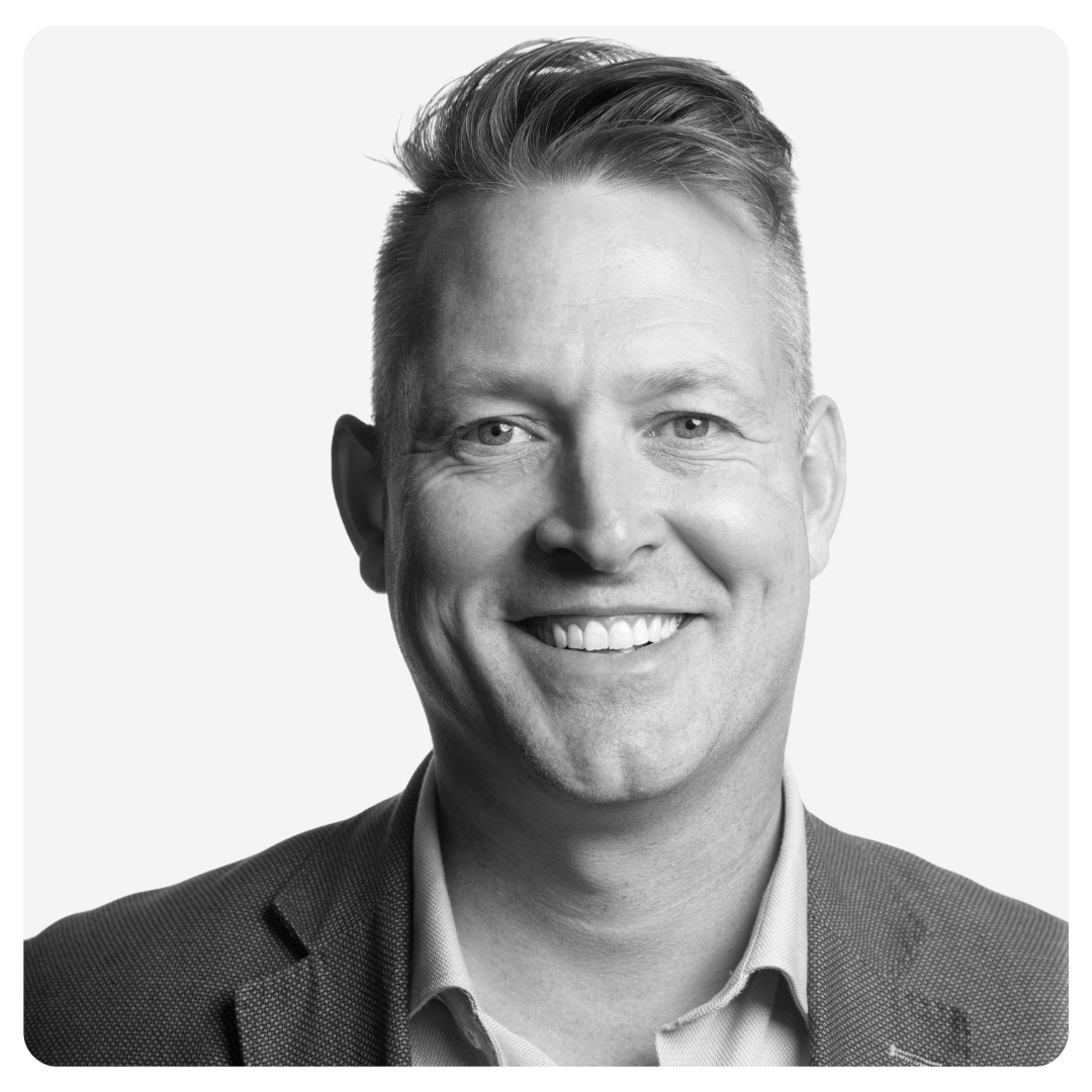 Smiling man with short, styled hair wearing a suit jacket and collared shirt, photographed against a plain white background, embodying professionalism and a commitment to safety in workplaces.